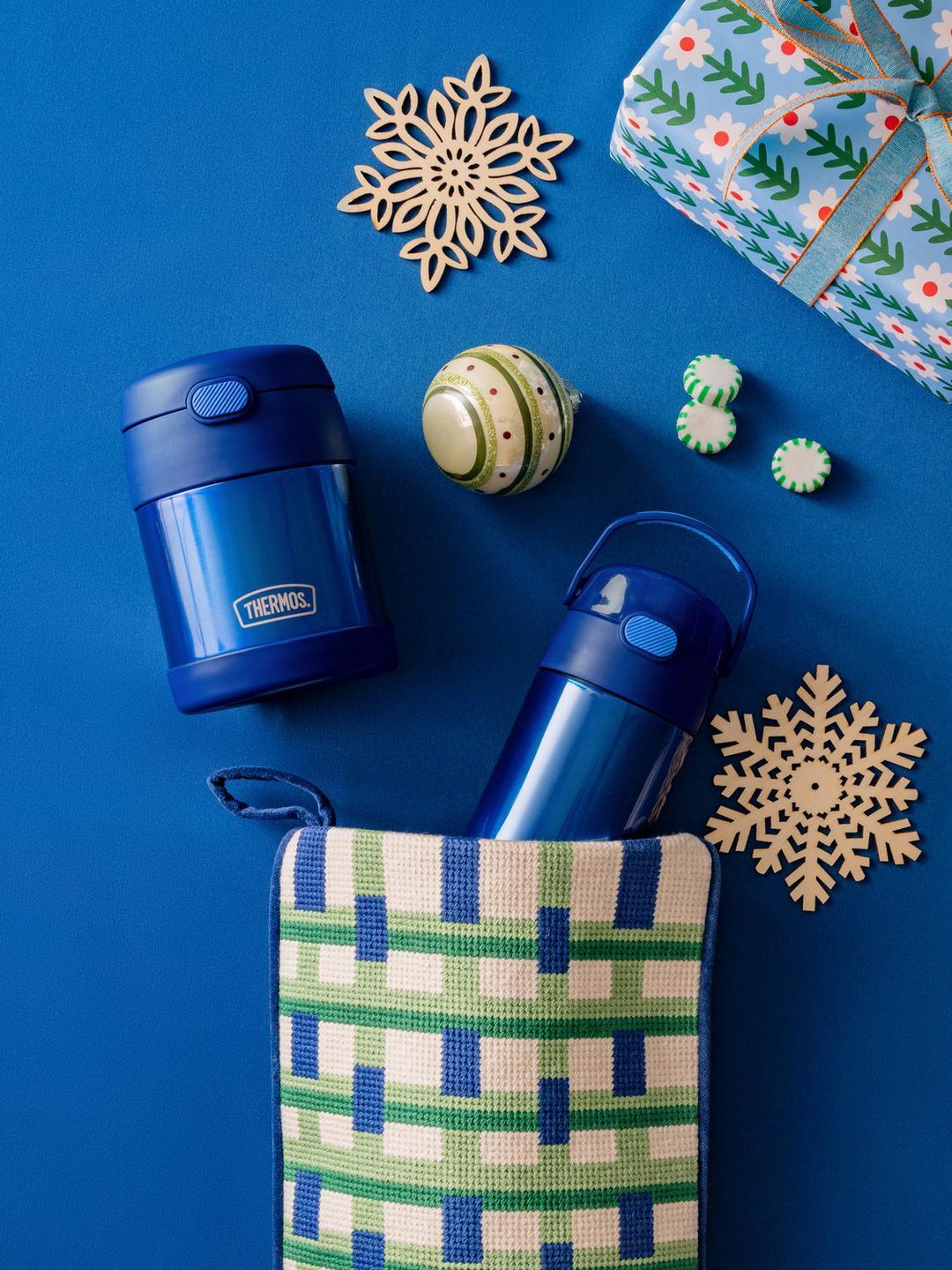 Blue thermos FUNtainer water bottle and food jar with decorative items on a blue background