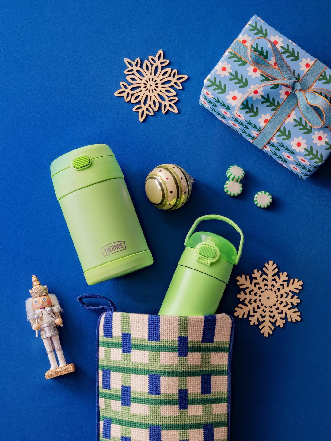 Neon Green Thermos FUNtainer water bottle and food jar, decorative box, snowflakes, and nutcracker on a blue background