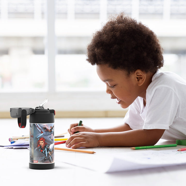 Boy sitting at a table coloring, with the 12 ounce Funtainer Avengers water bottle opened next to him.