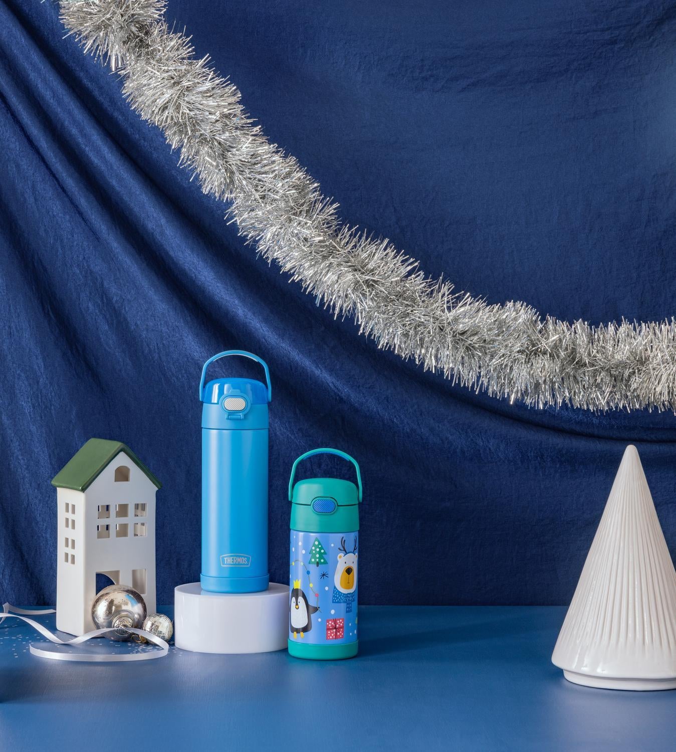 Two blue thermos bottles with festive decorations on a blue background