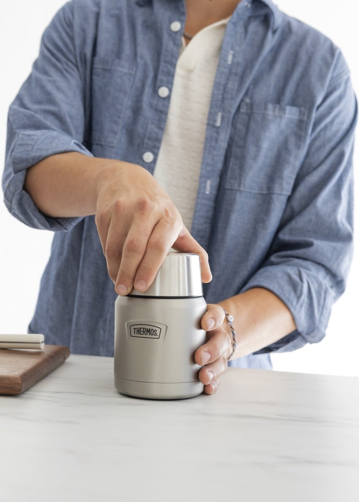 Person holding a Thermos Food jar on a white surface