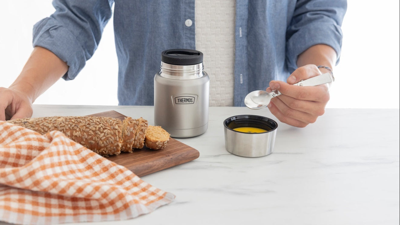 Person preparing food with a thermos on a white table