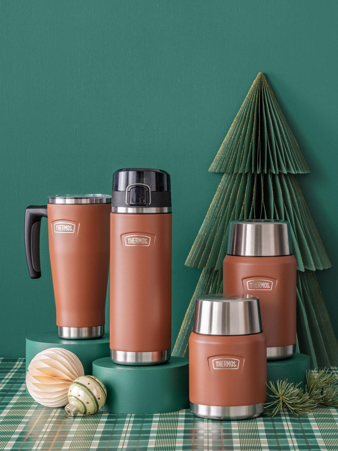Set of brown thermos bottles with silver bases on a green surface with decorative elements.