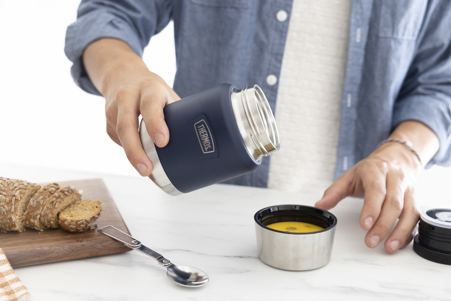 Person pouring food into the lid of the Icon Food Jar