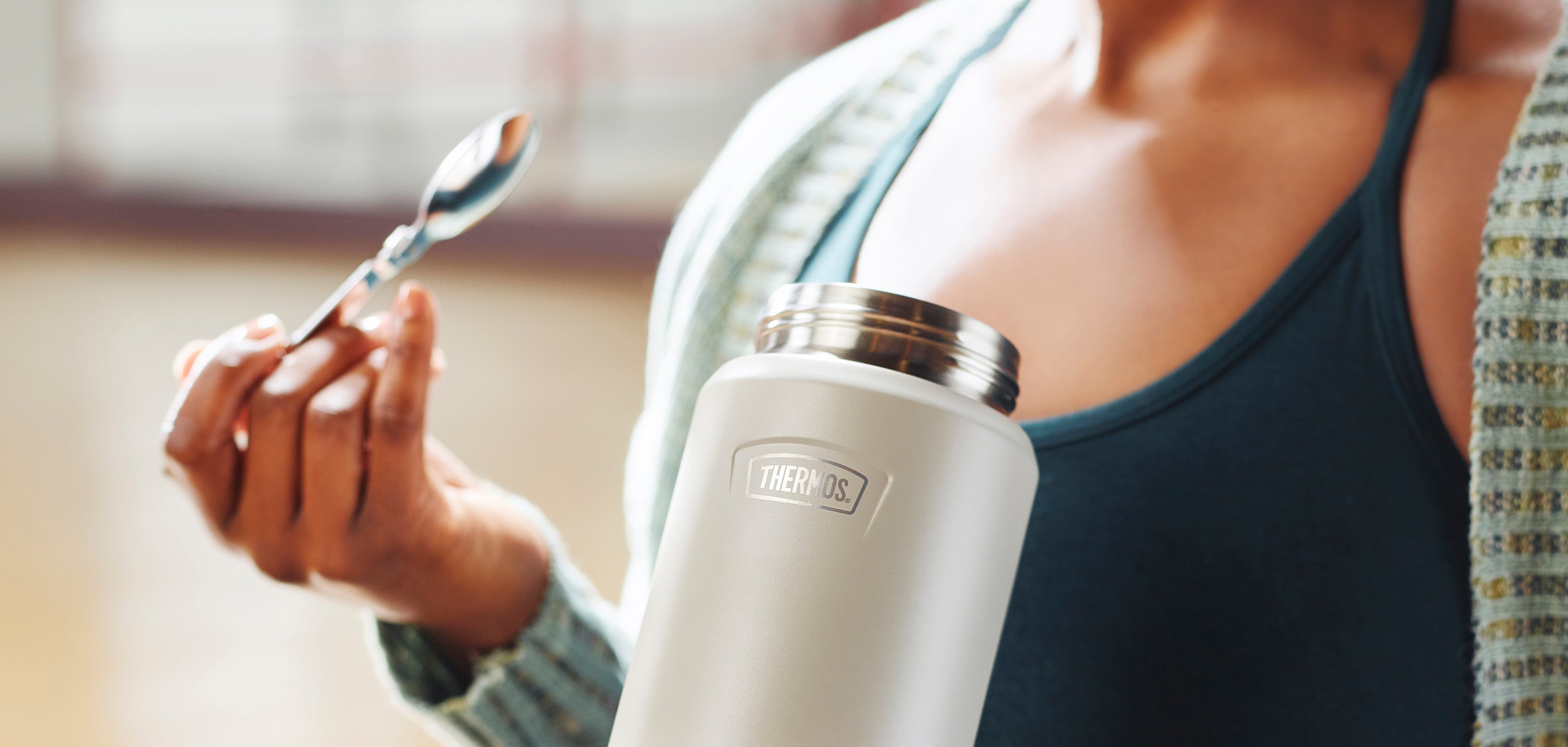 Person eating out of their Thermos food jar with a spoon.