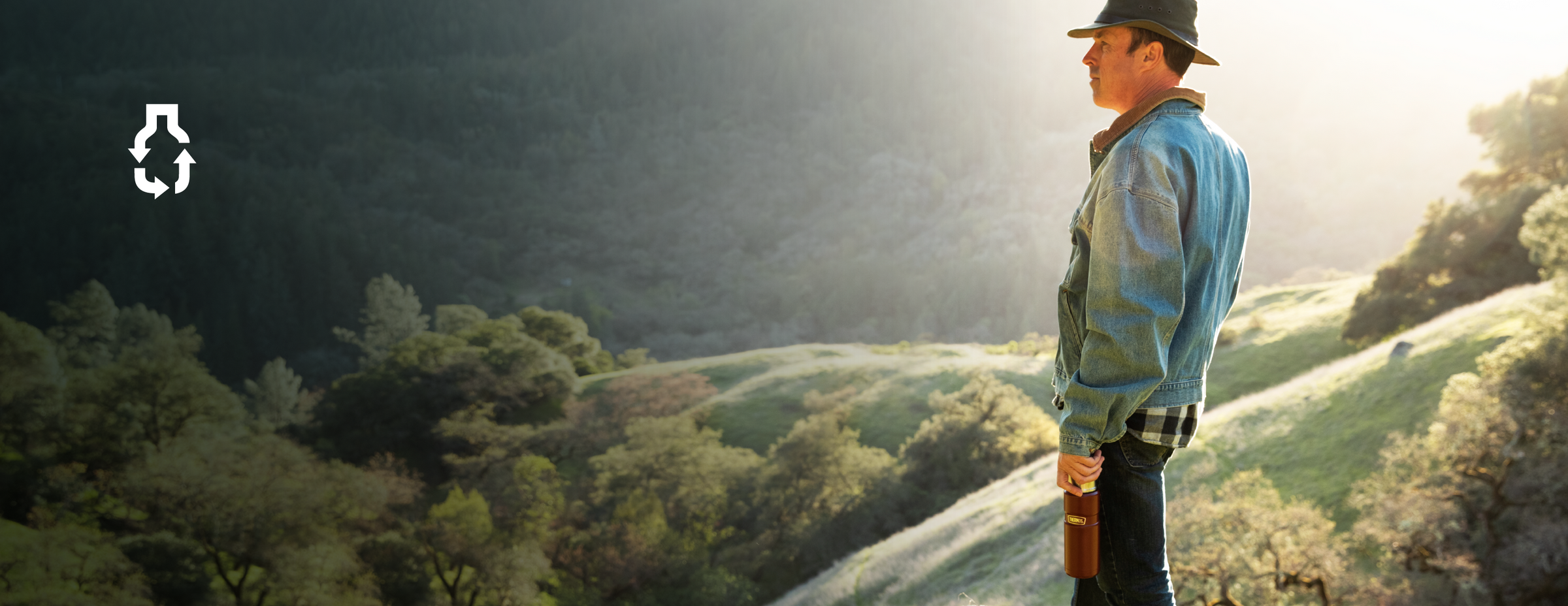 Man standing on mountain holding a Thermos Beverage Bottle.